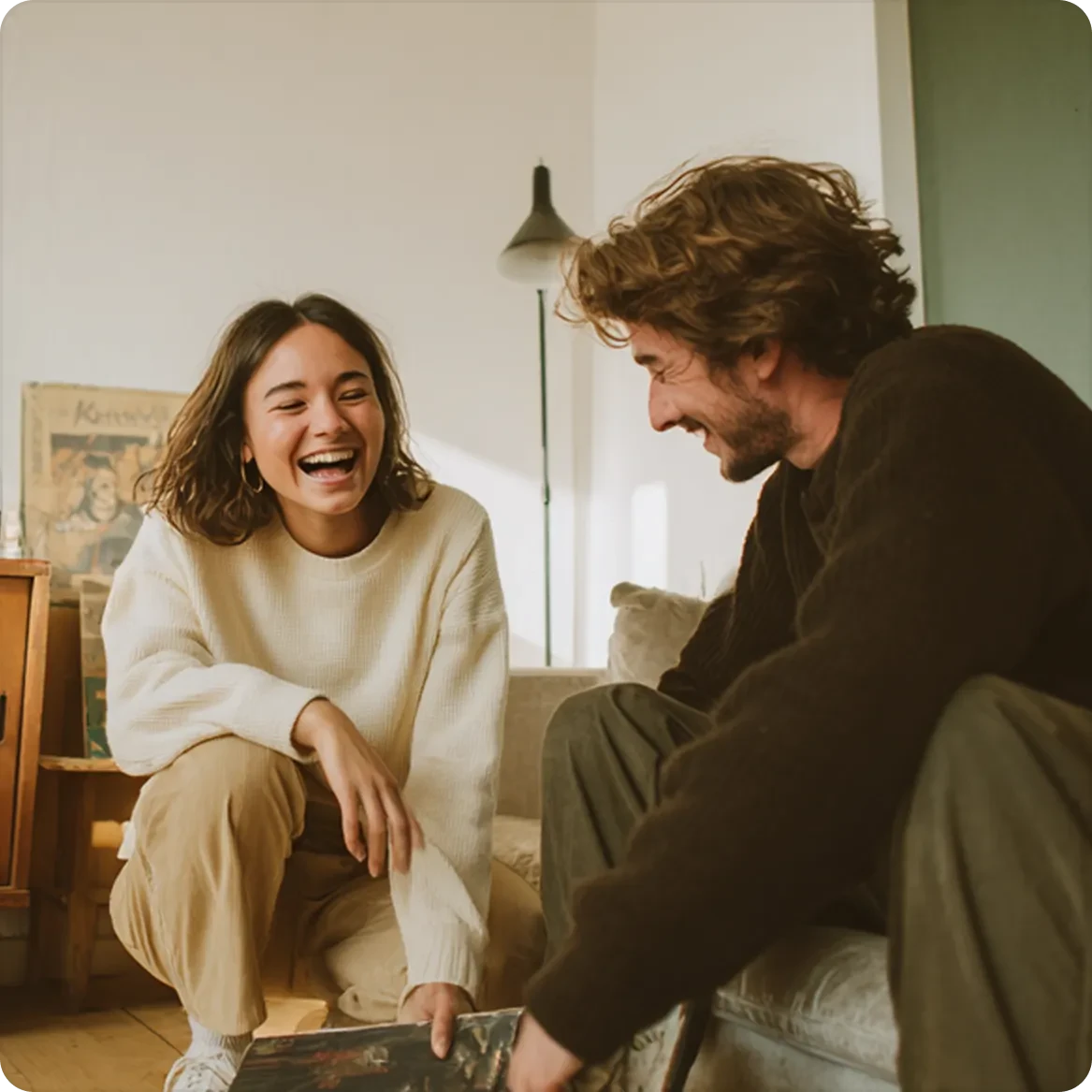 Couple laughing on couch in warm sunlit living room